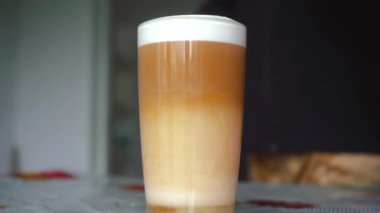 Adam bardakta kahve karıştırıyor.