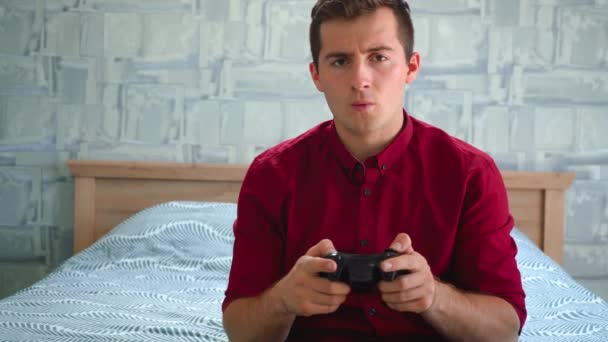 Pria duduk di sofa dan memainkan konsol video game — Stok Video