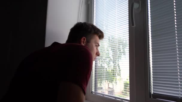 Homem olha pela janela de manhã — Vídeo de Stock