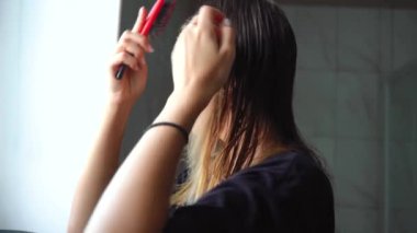 Kız banyoda saçını tarıyor.