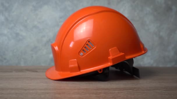 Oranje helm ligt op een houten tafel — Stockvideo