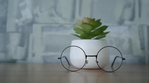 Gafas y soporte de flores en una cómoda de madera — Vídeos de Stock