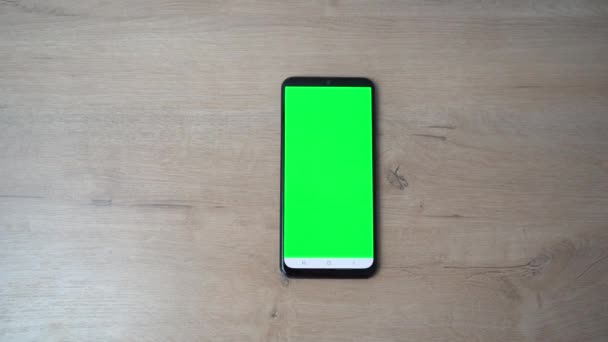 Telefonen med den grønne skærm er på træbordet – Stock-video