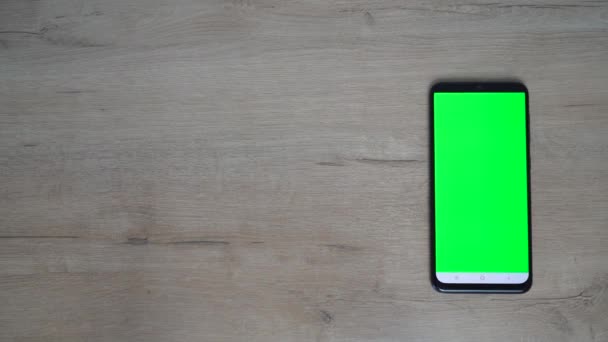 Teléfono negro con una pantalla verde se sienta en una mesa de madera. — Vídeos de Stock