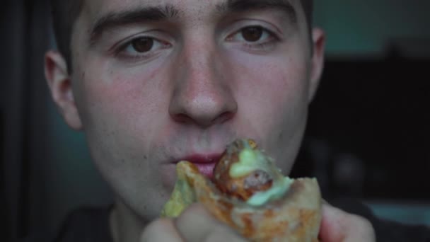 Молодой человек ест сладкую булочку — стоковое видео