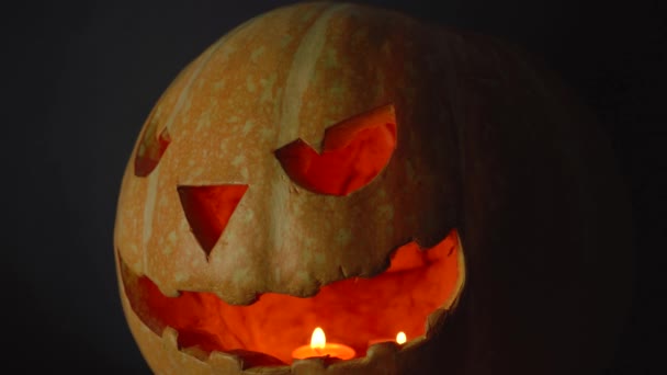 Halloween pompoen met een gesneden eng gezicht in de schemerkamer — Stockvideo