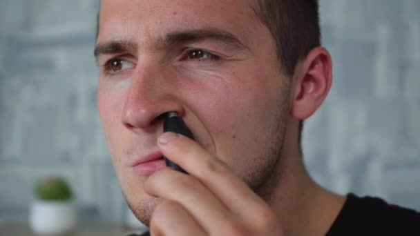 Un hombre se afeita el pelo de la nariz con un trimer especial — Vídeo de stock