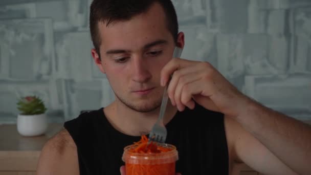 Человек ест корейскую морковку с тарелки — стоковое видео