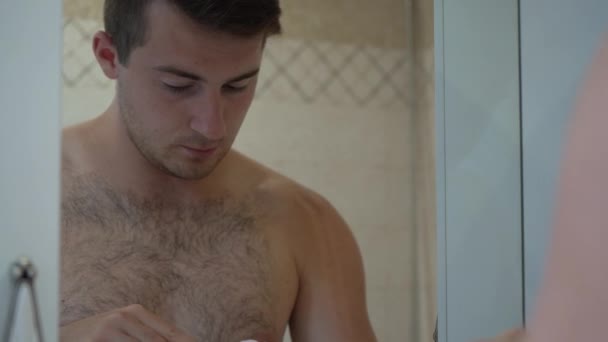 Un hombre se cepilla los dientes por la mañana en el baño — Vídeo de stock