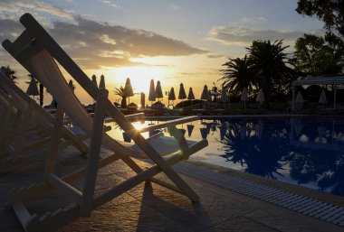 Birçok şafak gökyüzü ve plaj şemsiye zemin karşı yüzme havuz kenarında şezlong stand chaise beyaz