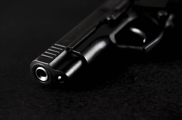 The black handgun lies on a black background