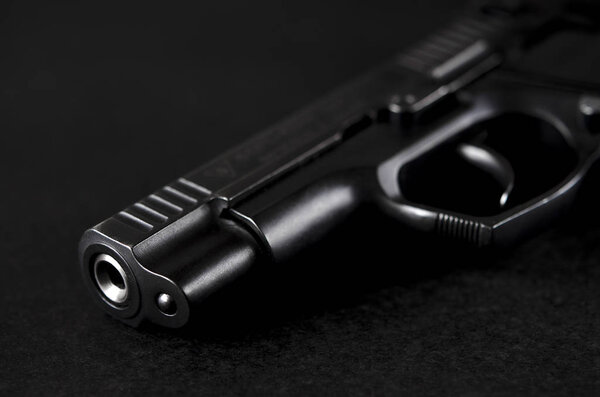 The black handgun lies on a black background