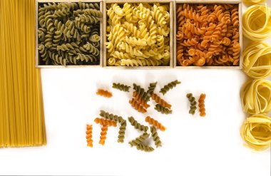 Spagetti ve tagliatelle yanında beyaz bir arka plan üzerinde renkli düdük ile üç ahşap kutusu vardır. izole