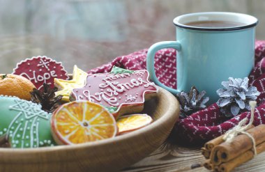 Plaka hangi gingerbread çerezleri portakal dilim su damlaları ile bir pencere arka planı yapılmış olan bir fincan sıcak çay yanında bir Ahşap ahşap bir masa üzerinde duruyor