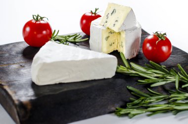 Ahşap tahta üzerinde çeşitli peynirler. Camembert, mavi küf ile peynir, domates ve biberiye mozzarella