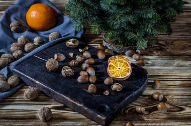 Ağaç, portakal, portakal dilimleri ve Bisküvi kar taneleri üzerinde hangi yalan ahşap masa fındık ile karanlık bir tahta yalan