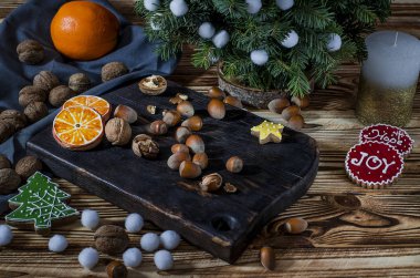 Noel kartı: ağaç, portakal, portakal dilimleri ve Bisküvi kar taneleri yalan üzerinde yatıyor fındık ile karanlık bir tahta ahşap masa üzerinde