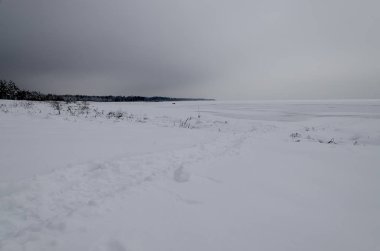 Karanlık kış gökyüzünde bir arka plan üzerine açık denize uzanan Karda izler