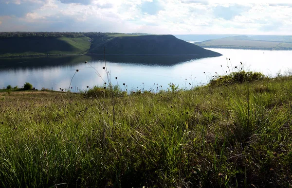 Yüksek sarp tepeler arasında büyük nehir Dniester akışı mavi gökyüzüne karşı bahar gür yeşil çim kaplı. Ukrayna