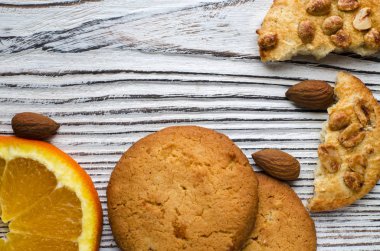 Renkli şekerlenmiş meyve ve sulu turuncu tahta bir masanın üzerinde yatan bir dilim ile yuvarlak portakal bisküvi. Portre