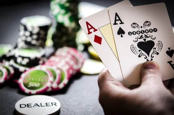 Siyah masada poker fişleri, kartları ve bir satıcı çip yalan. Kartları elini tutar