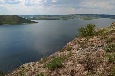 Yüksek sarp tepeler arasında büyük nehir Dniester akışı mavi gökyüzüne karşı bahar gür yeşil çim kaplı. Ukrayna