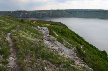 Yüksek sarp tepeler arasında büyük nehir Dniester akışı mavi gökyüzüne karşı bahar gür yeşil çim kaplı. Ukrayna