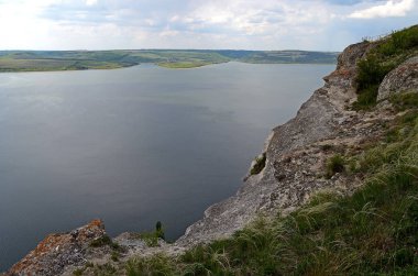 Yüksek sarp tepeler arasında büyük nehir Dniester akışı mavi gökyüzüne karşı bahar gür yeşil çim kaplı. Ukrayna