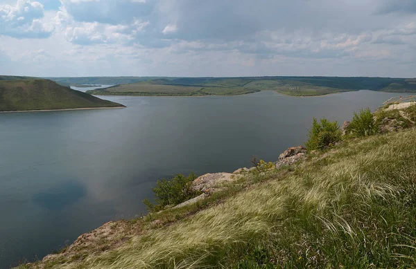 Yüksek sarp tepeler arasında büyük nehir Dniester akışı mavi gökyüzüne karşı bahar gür yeşil çim kaplı. Ukrayna