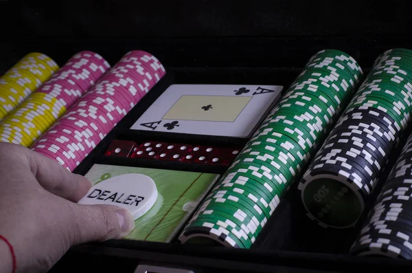 黒いテーブルの上のポーカー チップ カード ディーラー チップをあります 男の手がカードを保持します — ストック写真