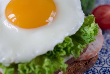 Günaydın. Domates ve dereotu ile bir tabakta yumurta, jambon, peynir, kızarmış ekmek ve salata yaprakları yalanlarla sandviç ile lezzetli kahvaltı