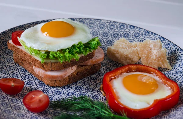 Günaydın. Domates ve dereotu ile bir tabakta yumurta, jambon, peynir, kızarmış ekmek ve salata yaprakları yalanlarla sandviç ile lezzetli kahvaltı