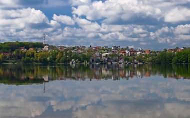 Bir köprü bir adanın ortasında bir göl üzerinde mavi gökyüzü bulutlu karşı uzun yeşil ağaçlar büyümeye yol açar