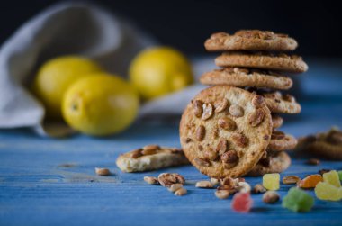 Renkli şekerlenmiş meyve ve sulu turuncu tahta bir masanın üzerinde yatan bir dilim ile yuvarlak portakal bisküvi