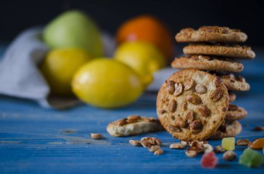 Renkli şekerlenmiş meyve ve sulu turuncu tahta bir masanın üzerinde yatan bir dilim ile yuvarlak portakal bisküvi