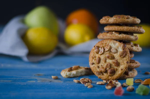 Round orange biscuits with colorful candied fruits and a slice of juicy orange lying on a wooden table — Stock Photo, Image