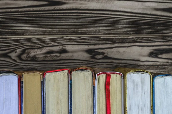 Lots of colourful thick open books stand on a dark background — Stock Photo, Image