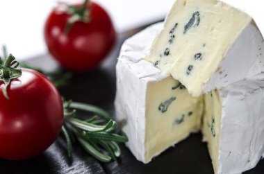 Ahşap tahta üzerinde çeşitli peynirler. Camembert, mavi küf ile peynir, domates ve biberiye mozzarella