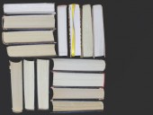 Mnoho vícebarevné tlusté otevřené knihy stojí na tmavém pozadí. Na knihách jsou staré kulaté brýle a otevřený zápisník s tužkou.