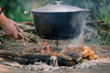 Bir erkek eli altında bir ateşe standları bir pan yangın kindles.