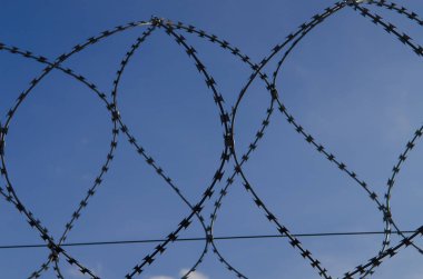 Beyaz bulutlar ile mavi bir gökyüzünde metal dikenli tel