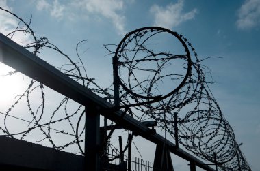 Beyaz bulutlar ile mavi bir gökyüzünde metal dikenli tel