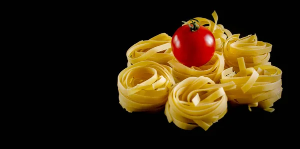 Round balls of raw pasta with tomato on black background. isolated. — Stock Photo, Image
