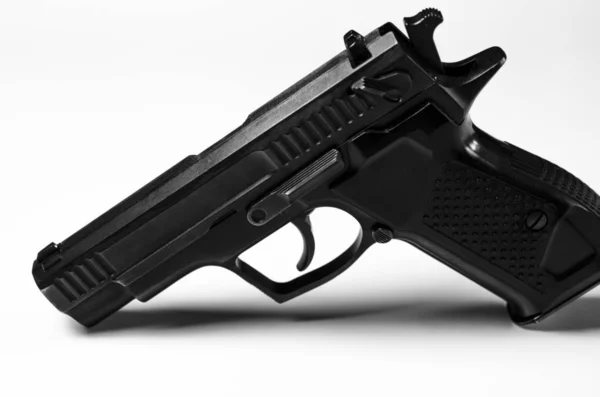 Pistola de metal negro se encuentra sobre un fondo blanco, primer plano —  Fotos de Stock