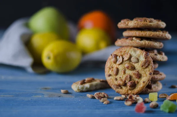 Round orange biscuits with colorful candied fruits and a slice of juicy orange lying on a wooden table — Stock Photo, Image