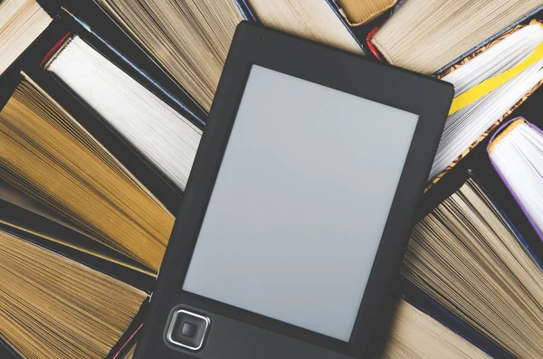De e-boek met een wit scherm ligt op de open multi-gekleurde boeken die liggen op een donkere achtergrond, close-up — Stockfoto