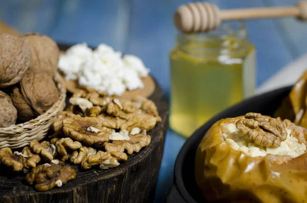 Здорова їжа. Запечені яблука з сиром і горіхами лежать в чорній випічці на синьому дерев'яному столі — стокове фото