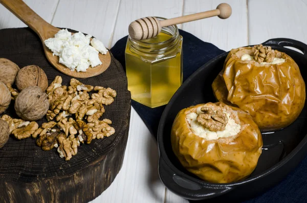Здорова їжа. Запечені яблука з сиром і горіхами лежать в чорній випічці на білому дерев'яному столі — стокове фото