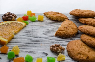 Renkli şekerlenmiş meyve ve sulu turuncu ahşap bir masa kış orman arka planı üzerinde yatan bir dilim ile yuvarlak portakal bisküvi