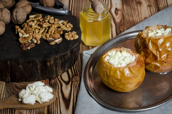 sağlıklı gıda. Süzme peynir ve fındık ile pişmiş elma ahşap bir masa üzerinde siyah bir pişirme çanağı yalan